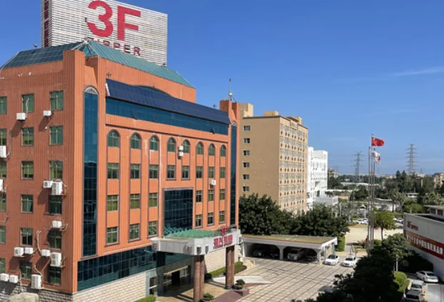 3F Zipper company building with prominent signage on top, displaying a large red '3F' and the word 'ZIPPER', surrounded by a clear blue sky and neighboring buildings.