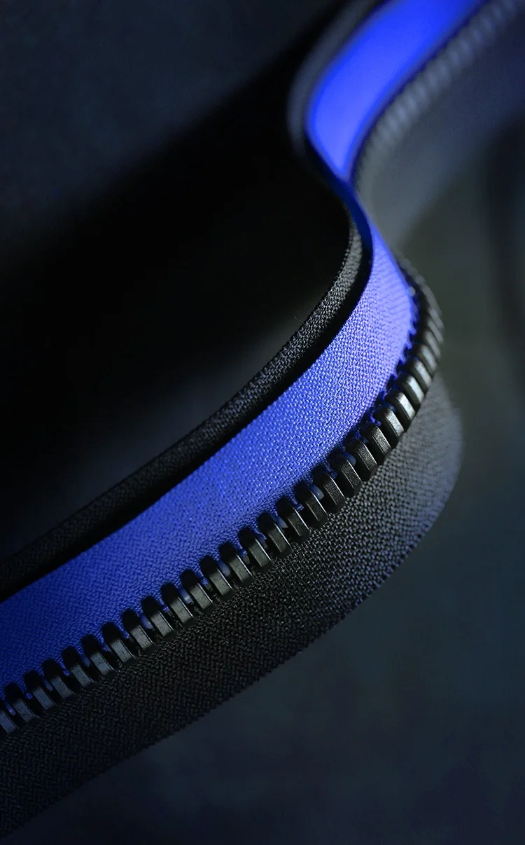Close-up view of a blue zipper with black teeth against a dark background, highlighting the texture and grooves.