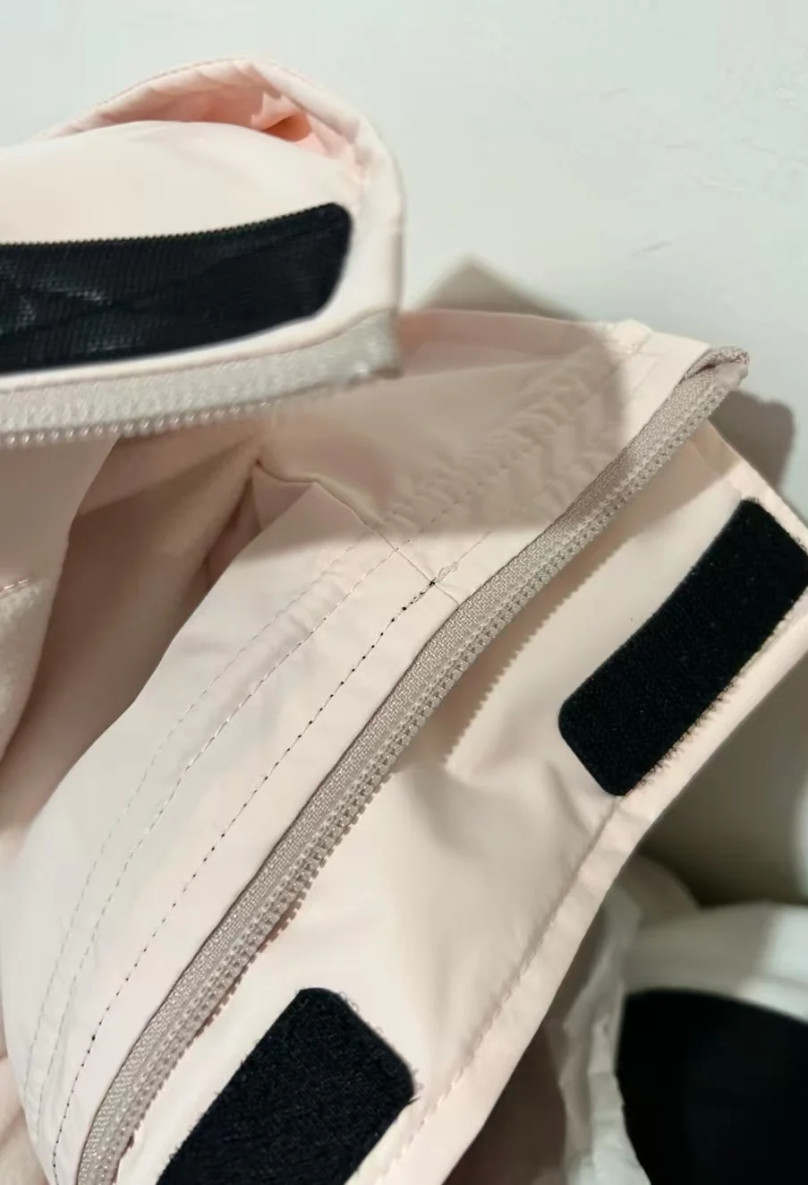 Detailed view showing the velcro and zipper on a light pink jacket, emphasizing garment accessories provided by Shenzhen Holyn Textile Co., Ltd.