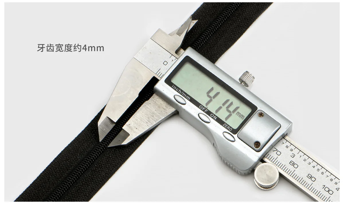 Digital caliper measuring the width of a black zipper, showing 4.14 mm on the screen, representing precision in garment accessories measurement.