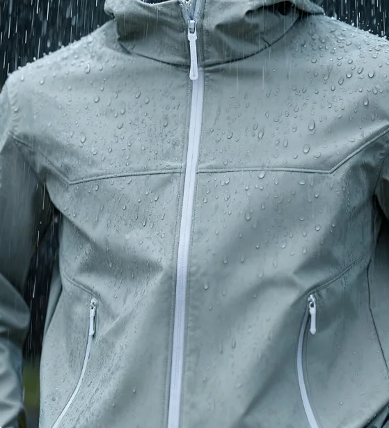 Close-up of a grey waterproof jacket with water droplets during rain, highlighting its water-resistant material and design.