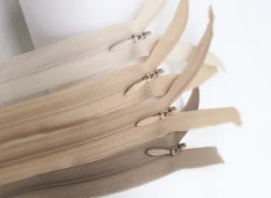 A selection of zippers in various beige tones displayed on a white background, showcasing different shades and textures.