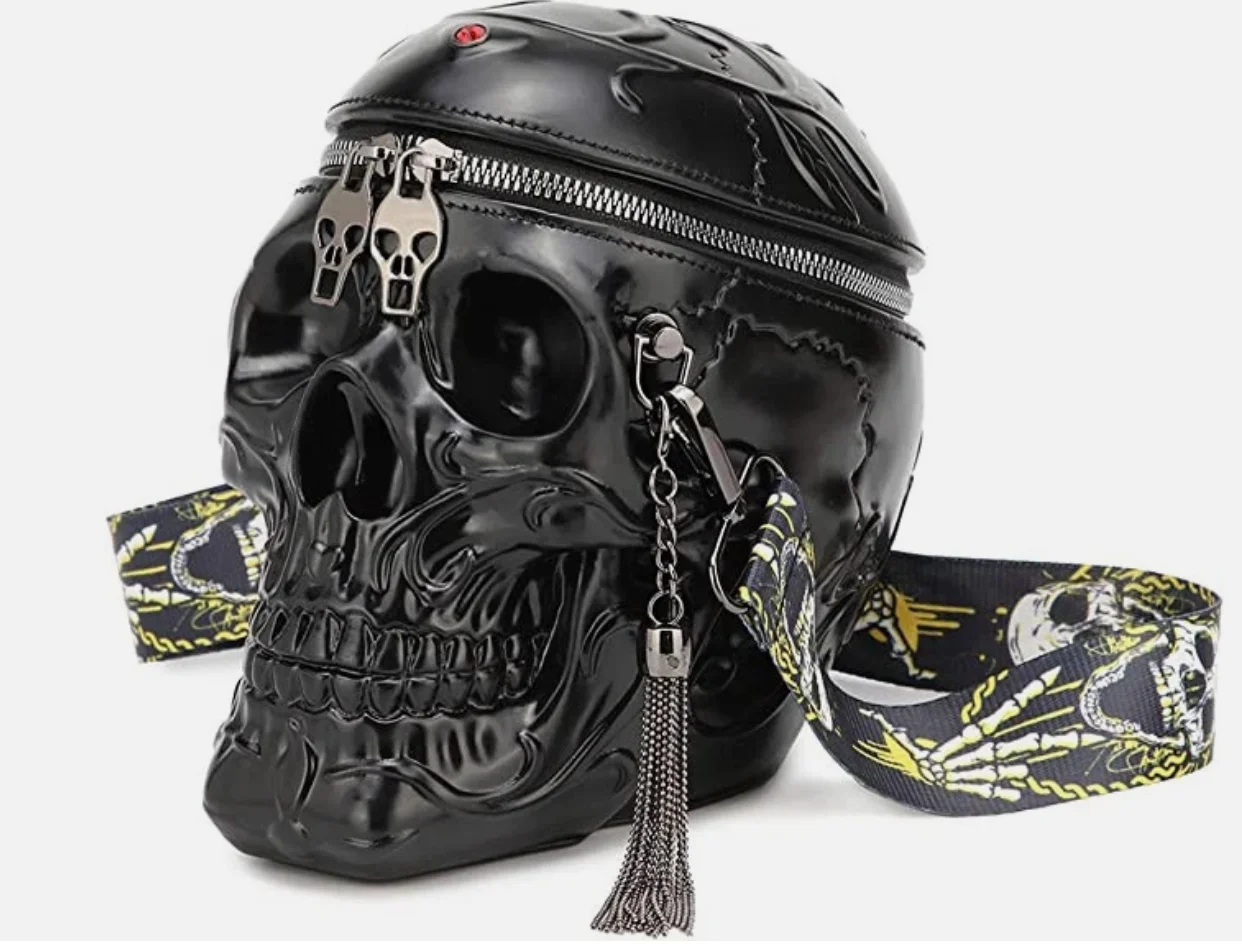 Black skull-shaped bag with zipper closure, decorative tassel, and colorful strap featuring skull designs.