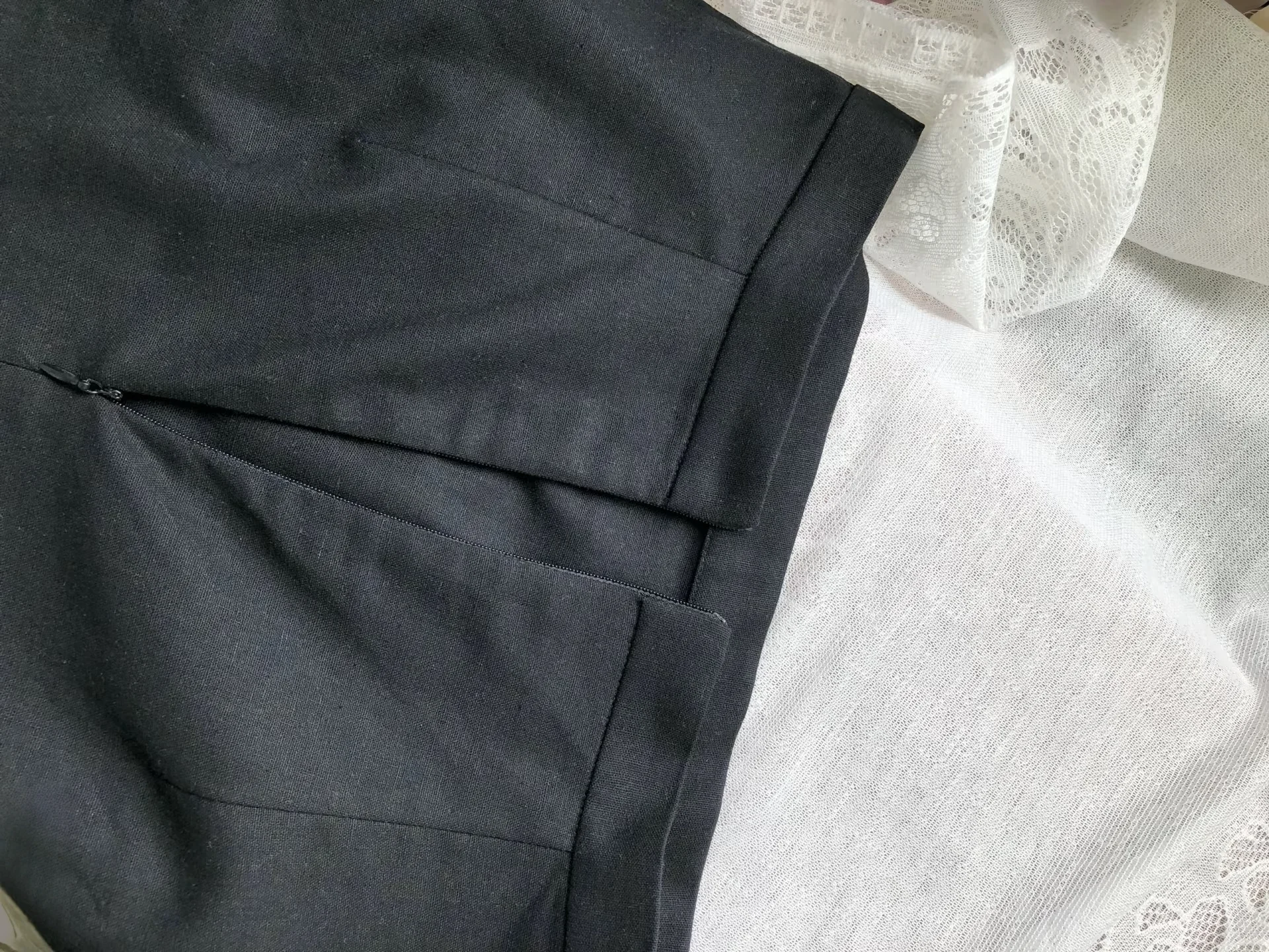 Close-up of black trousers folded neatly with white lace fabric in the background, showcasing textile textures.