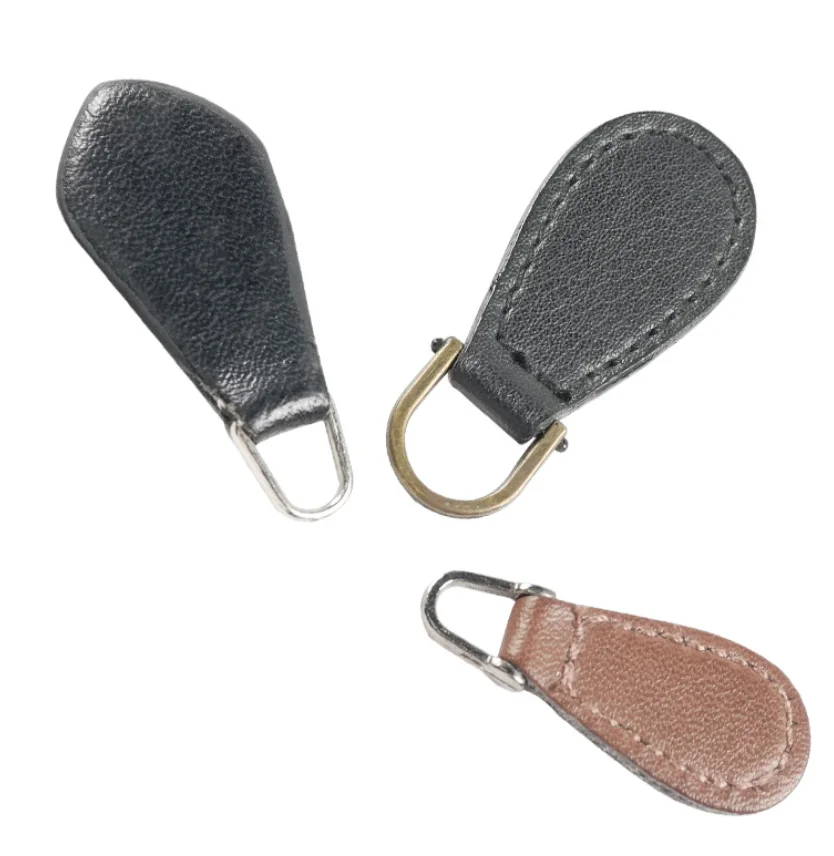 Three leather zipper pulls in black and brown with metal loops on white background.
