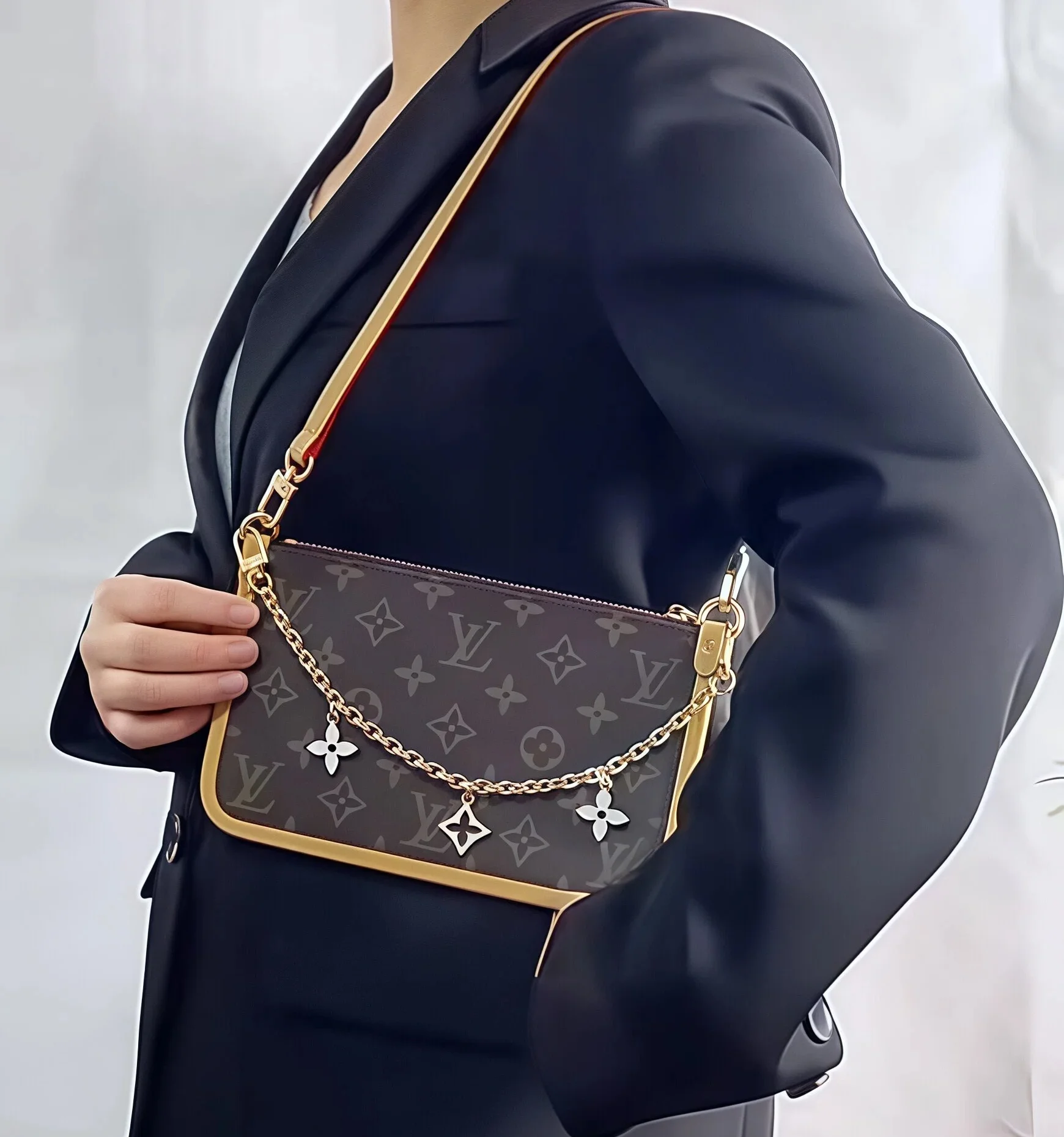 Person holding a luxury handbag with monogram pattern and decorative chain strap, wearing a dark blazer.