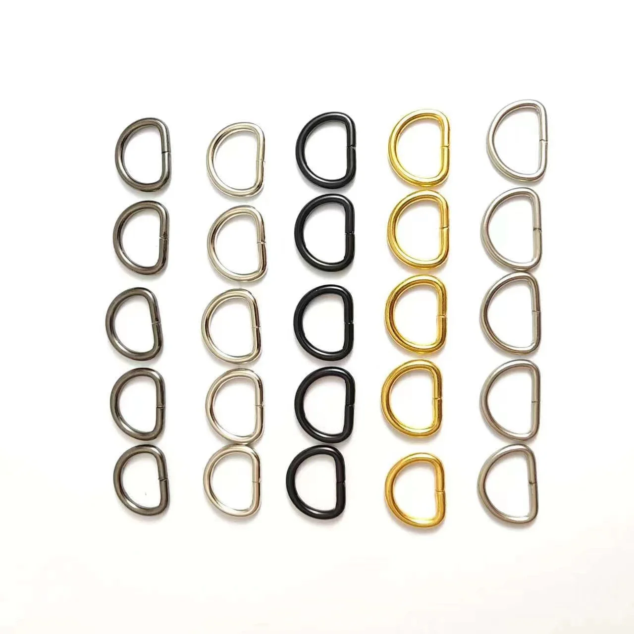 Rows of assorted metal D-rings in various colors including silver, black, and gold, arranged on a white background.