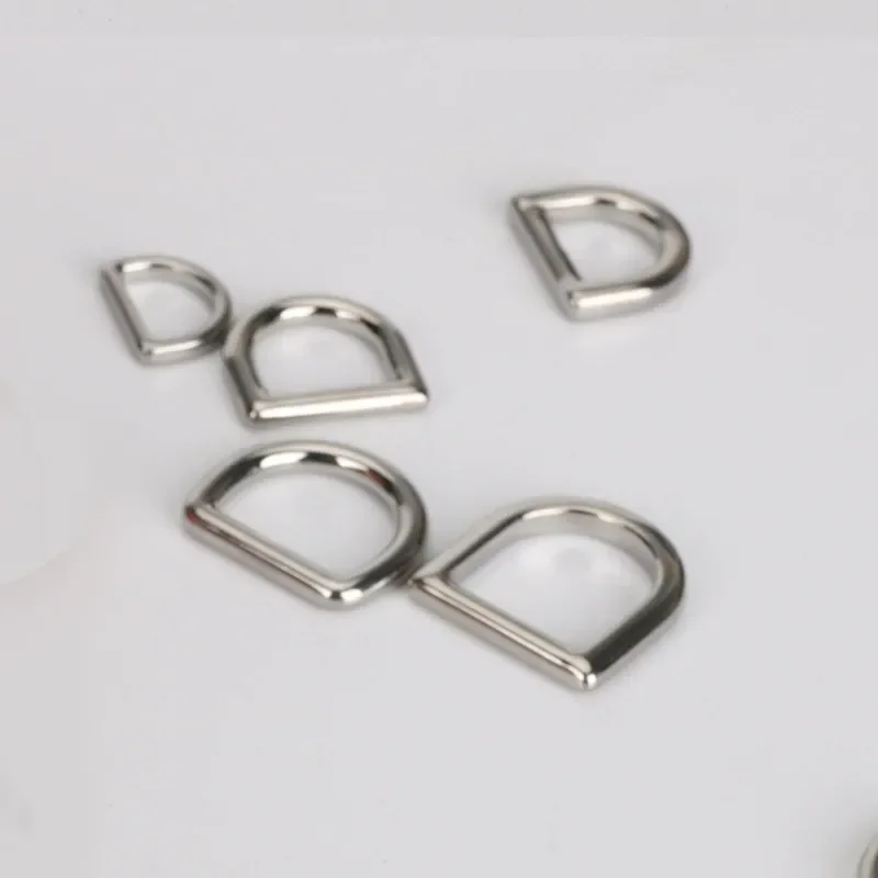 Assorted metal D-rings in various sizes displayed on a white surface, used for fastening in garments and bags.