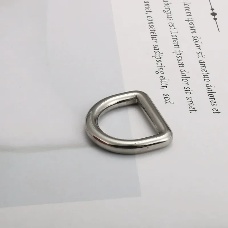 A shiny metal D-ring typically used for garment and bag accessories, placed on a sheet of text-covered paper.