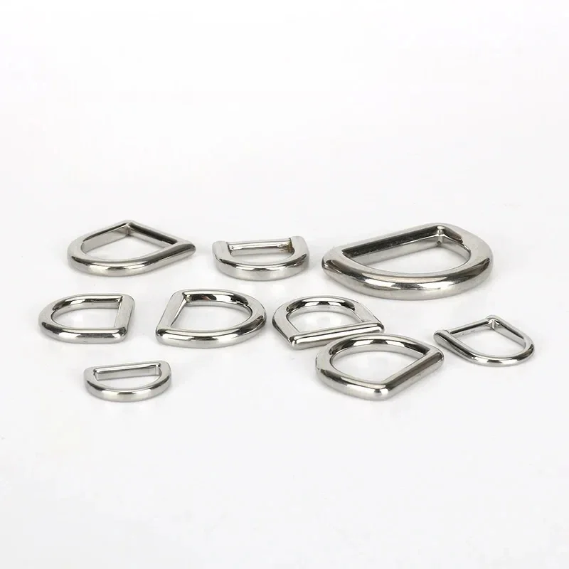 Array of silver metal D-rings in various sizes displayed on a white surface showcasing garment and bag accessory components.
