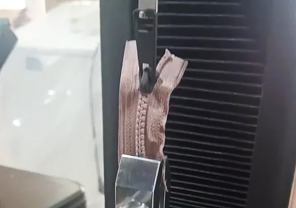 Zipper undergoing a strength test on a testing machine, showcasing its durability and quality.