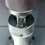 Close-up of a zipper being tested on a professional industrial machine to assess its durability and performance.